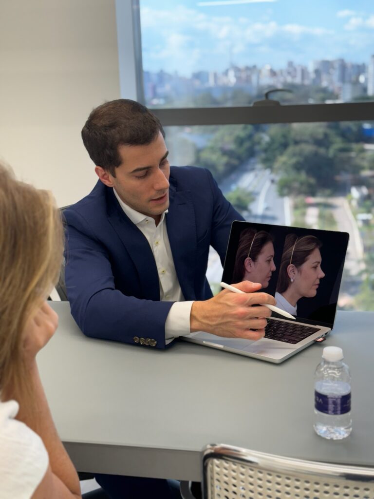 Dr. João Carlos Pereira Filho em consulta mostrando planejamento de Deep Plane Face Lift em tela de computador para paciente