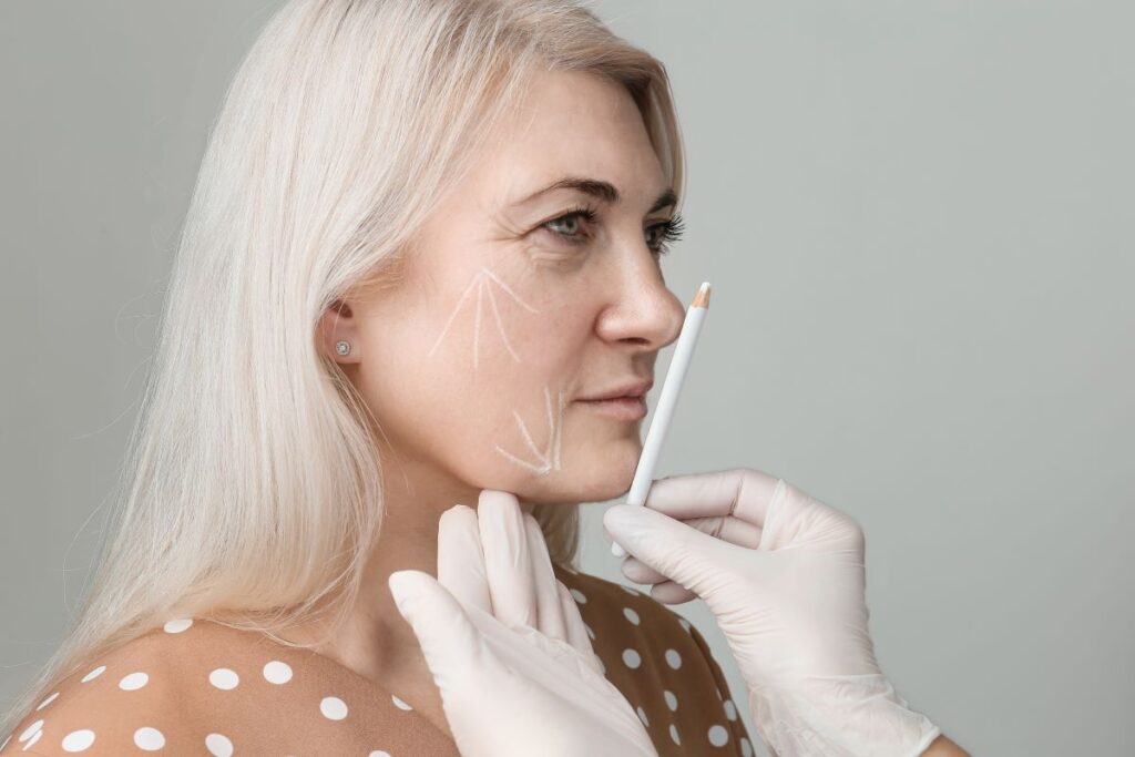 Mulher mais velha de cabelos branco sendo fazendo análise facial para cirurgia plástica.