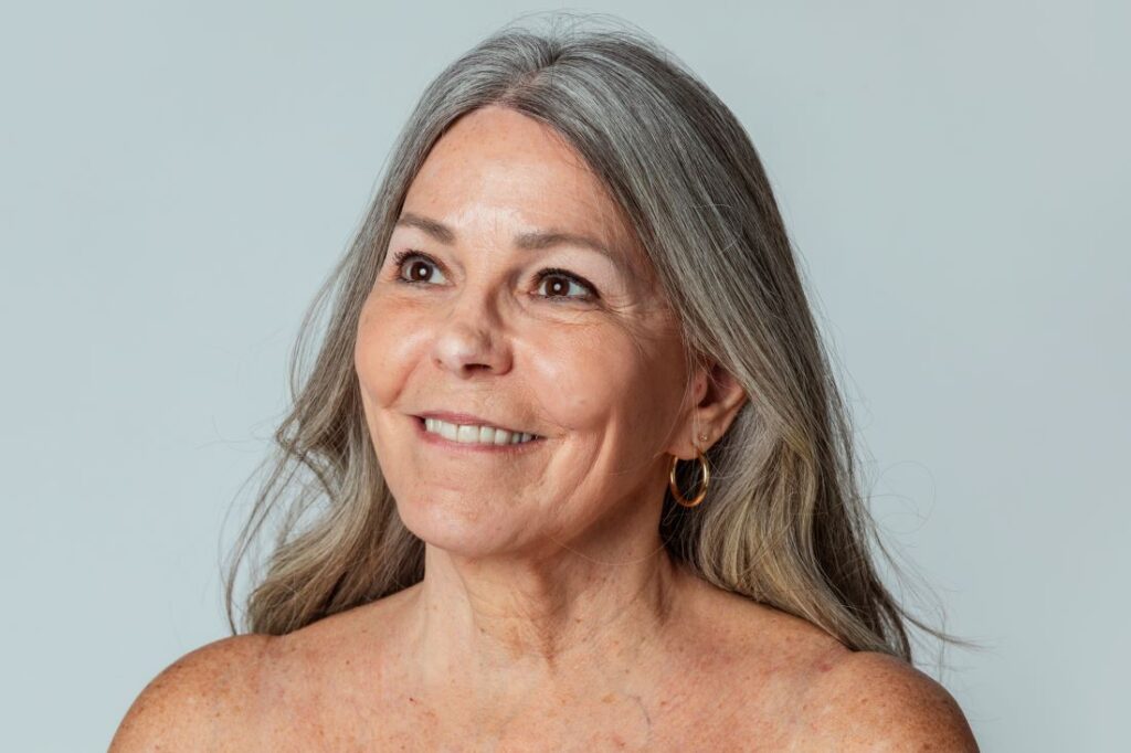 Mulher idosa e cabelo grisalho com pele levemente esticada.