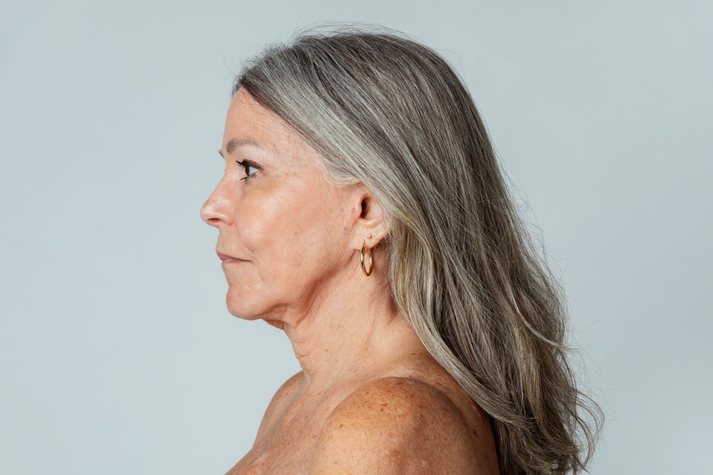 Mulher idosa em perfil destaca a linha da mandíbula e os contornos faciais relacionados ao envelhecimento da pele.