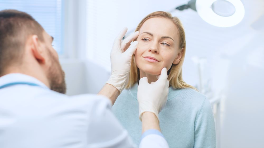 Médico avalia rosto de paciente durante consulta sobre bioestimulador de colágeno e rejuvenescimento facial.